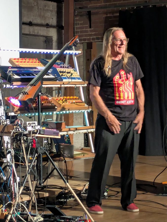 Jeff Boynton standing beside his rack of circuit-bent instruments
