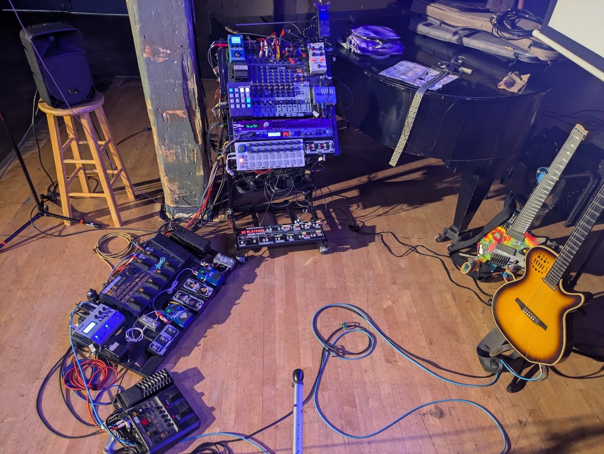 Pedalboards, mixer and a guitar on a stage floor